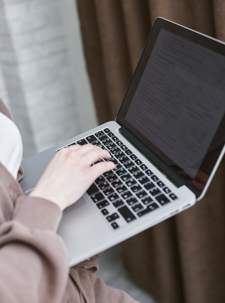 A person typing on a laptop indoors, focusing on the keyboard.